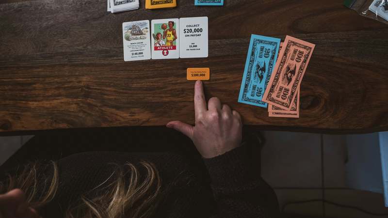 Two hands holding a joint credit card with overlapping signatures and a clean financial dashboard in background